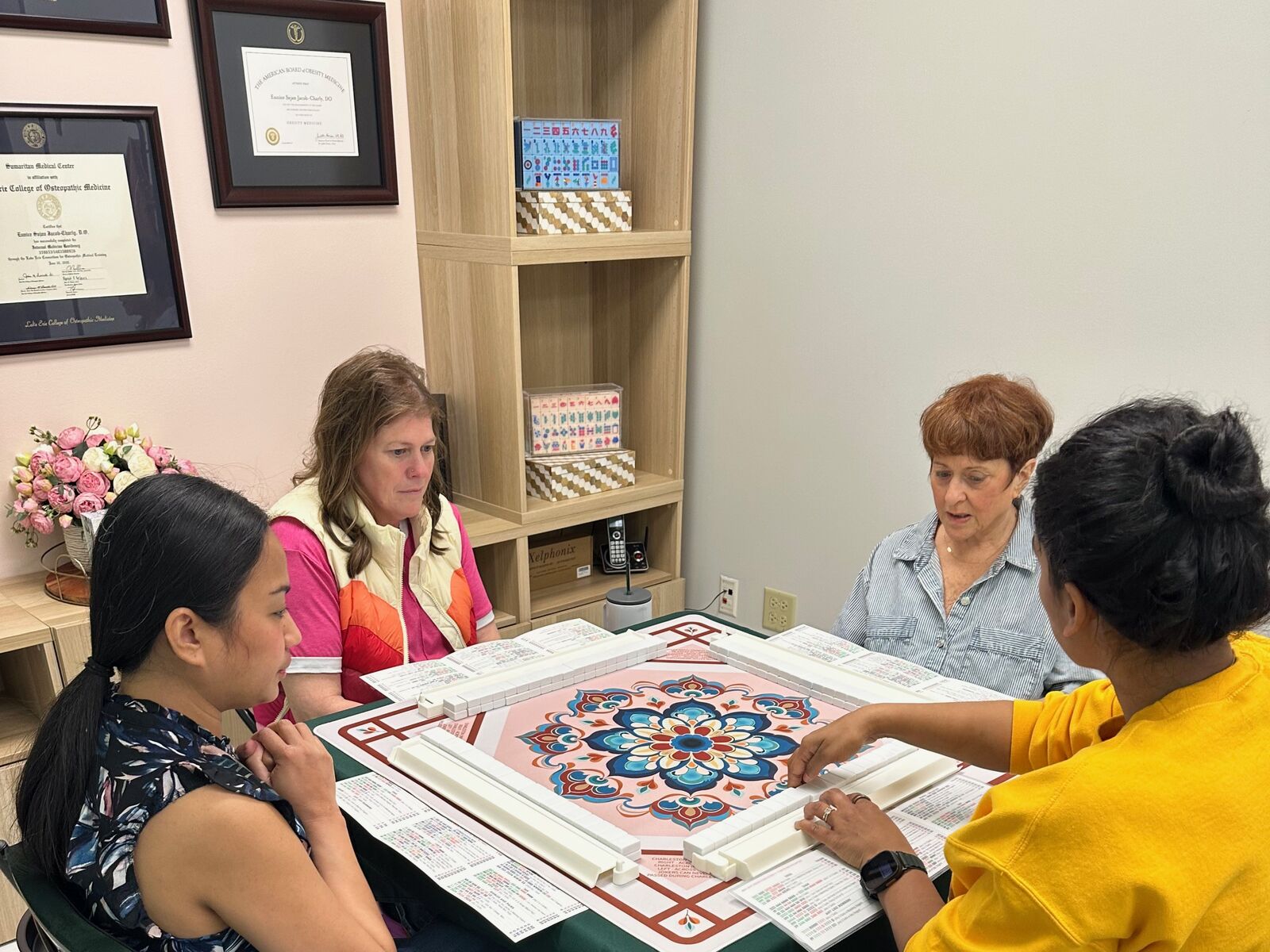 Four players gathered around a mandala-print Mahjong mat at the Unique Mahjong Parlor